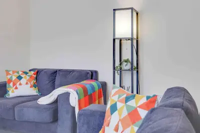 a living room with two blue couches and a lamp at Elm Cottage Ipswich in Ipswich