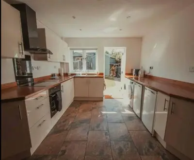 a large kitchen with white cabinets and a tile floor at Charming 2 Bedroom Cottage mid town on quiet road, sleeps 4 in Sudbury