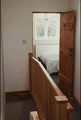a bedroom with a bed and a stairway with a door at Charming 2 Bedroom Cottage mid town on quiet road, sleeps 4 in Sudbury
