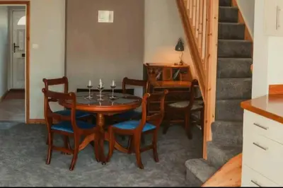 a dining room with a table and chairs and a staircase at Charming 2 Bedroom Cottage mid town on quiet road, sleeps 4 in Sudbury