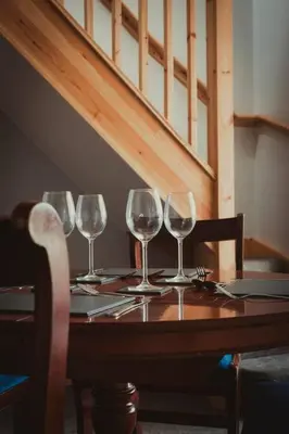 four wine glasses sitting on a wooden table at Charming 2 Bedroom Cottage mid town on quiet road, sleeps 4 in Sudbury
