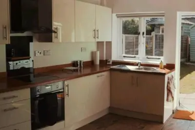 a kitchen with white cabinets and a sink at Charming 2 Bedroom Cottage mid town on quiet road, sleeps 4 in Sudbury