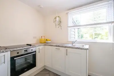 a kitchen with white cabinets and a sink and a window at 6 Uplands in Thorpeness