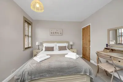 a white bedroom with a large bed and a desk at Delightful 10 St Martins - 2 bed, 2 bathroom with parking available in Bury Saint Edmunds