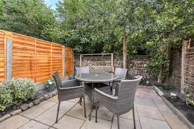 a patio with a table and chairs and a fence at Delightful 10 St Martins - 2 bed, 2 bathroom with parking available in Bury Saint Edmunds
