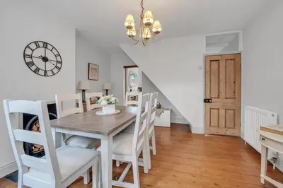 a dining room with a table and chairs and a clock at Delightful 10 St Martins - 2 bed, 2 bathroom with parking available in Bury Saint Edmunds