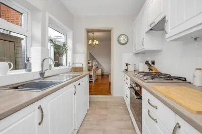a white kitchen with a sink and a stove at Delightful 10 St Martins - 2 bed, 2 bathroom with parking available in Bury Saint Edmunds