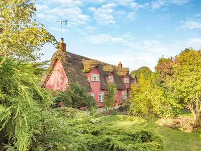 a large red house with a thatched roof at All Saints Cottage in Saffron Walden