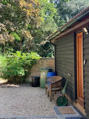 a bench next to a house with a trash can and a garbage can at Tasburgh - Farthings in Norwich