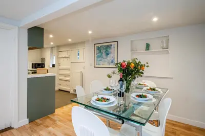 a dining room with a glass table and white chairs at 10 Hertford Place in Aldeburgh