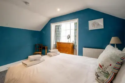 a bedroom with a large white bed with blue walls at 10 Hertford Place in Aldeburgh