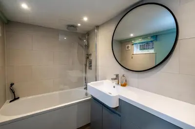 a bathroom with a sink and a mirror and a tub at 10 Hertford Place in Aldeburgh