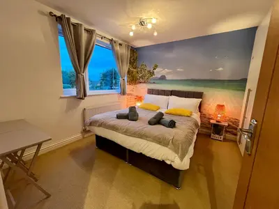 a bedroom with a bed with a painting on the wall at The Palm Tree House in St Ives