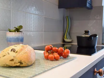 a loaf of bread and tomatoes on a counter in a kitchen at Caines Cottage in Saxmundham