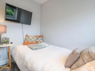 a bedroom with a bed with a tv on the wall at Caines Cottage in Saxmundham