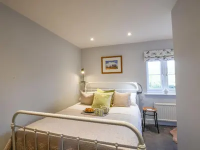 a bedroom with a bed and a window at Caines Cottage in Saxmundham