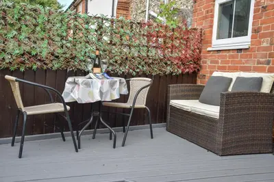 a table and chairs with a bottle of wine on it at Caines Cottage in Saxmundham