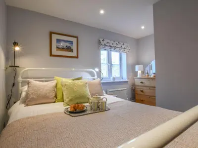 a bedroom with a bed with a tray of food on it at Caines Cottage in Saxmundham