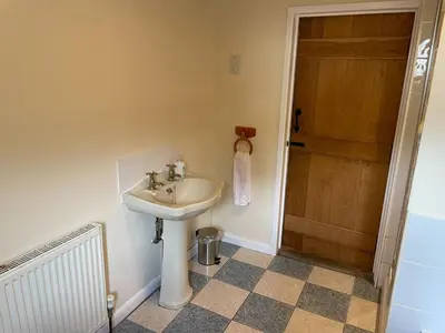 a bathroom with a sink and a wooden door at Kings Barn - English Countryside Retreat in Lindsell
