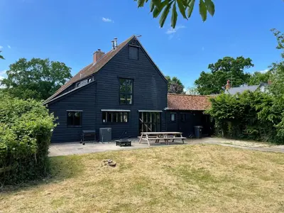 a black house with a picnic table in the yard at Kings Barn - English Countryside Retreat in Lindsell