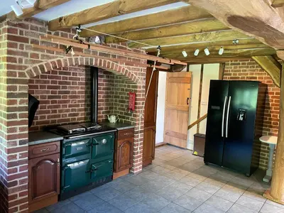 a kitchen with a black refrigerator and a brick wall at Kings Barn - English Countryside Retreat in Lindsell
