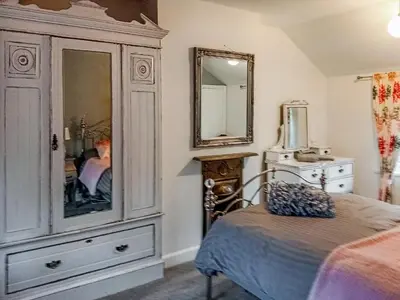 a bedroom with a large dresser and a mirror at Ivy Rose Cottage in Ipswich