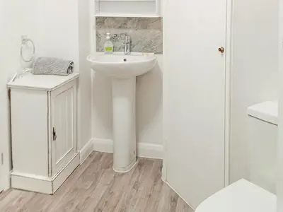 a white bathroom with a sink and a toilet at Ivy Rose Cottage in Ipswich