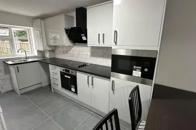 a kitchen with white cabinets and a table and chairs at Diamond House in Friern Barnet