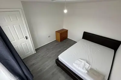 a bedroom with a white bed with a wooden floor at Diamond House in Friern Barnet