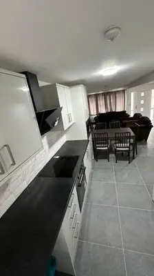 a kitchen with black and white cabinets and a living room at Diamond House in Friern Barnet