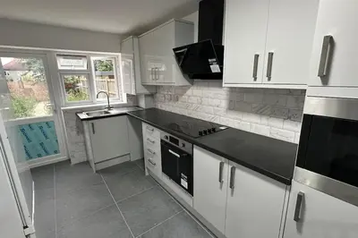 a kitchen with white cabinets and a black counter top at Diamond House in Friern Barnet