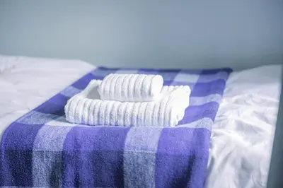 two towels on a blue and white blanket on a bed at Charming Family-Friendly 3-Bedroom House with Parking & Spacious Garden in Milton