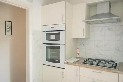 a kitchen with white cabinets and a stove top oven at Charming Family-Friendly 3-Bedroom House with Parking & Spacious Garden in Milton