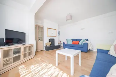 a living room with a blue couch and a tv at Charming Family-Friendly 3-Bedroom House with Parking & Spacious Garden in Milton