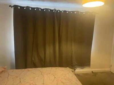 a bedroom with a window with a green curtain at Double room in Canvey island with shared bathroom in Hadleigh