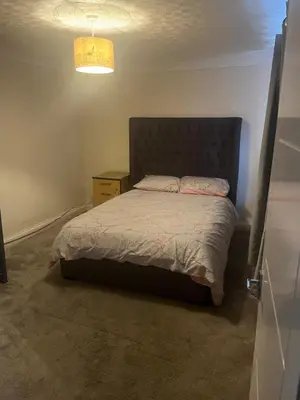 a bedroom with a bed and a lamp at Double room in Canvey island with shared bathroom in Hadleigh