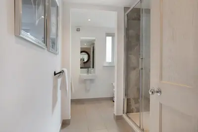 a bathroom with a shower and a glass door at Orchard Cottage in Saint Osyth