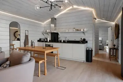 a living room with a table and a kitchen at Orchard Cottage in Saint Osyth