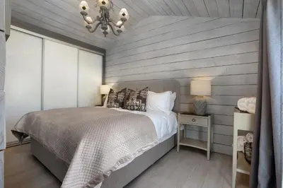 a bedroom with a large bed and a chandelier at Orchard Cottage in Saint Osyth