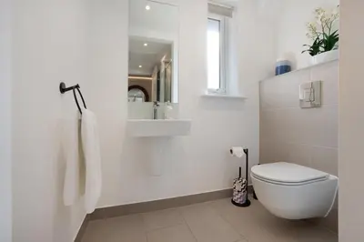 a white bathroom with a toilet and a sink at Orchard Cottage in Saint Osyth
