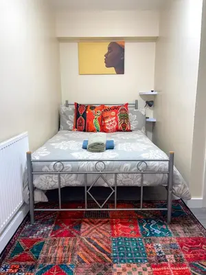 a bed in a room with a rug at Penn Gardens Standard Room - 4 in Friern Barnet