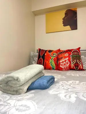 a bedroom with a bed with colorful pillows at Penn Gardens Standard Room - 4 in Friern Barnet