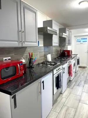 a kitchen with white cabinets and a red microwave at Penn Gardens Spacious king size room- 3 in Friern Barnet