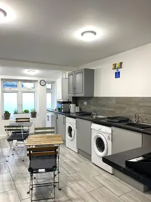 a kitchen with washing machines and a table and chairs at Penn Gardens Spacious king size room- 3 in Friern Barnet