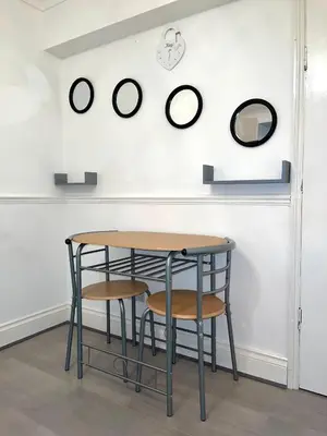 a table and two chairs and a wall with clocks at Penn Gardens Spacious king size room- 3 in Friern Barnet