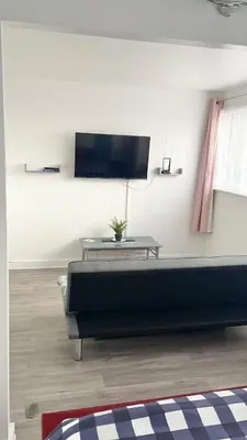 a living room with a bed and a tv on a wall at Penn Gardens 2 beds Apartment-2 in Friern Barnet