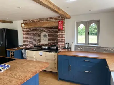 a kitchen with blue cabinets and a brick wall at Old Cottage - English Countryside Retreat in Lindsell