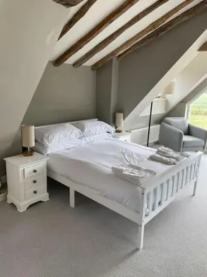 a bedroom with a white bed and a chair at Old Cottage - English Countryside Retreat in Lindsell