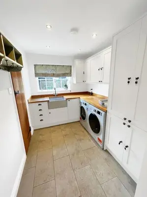 a kitchen with white cabinets and a washer and dryer at Mallards - English Countryside Retreat in Lindsell