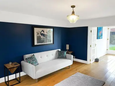 a living room with a white couch and a blue wall at Mallards - English Countryside Retreat in Lindsell
